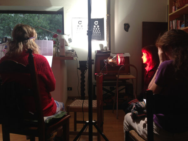 In caso di maltempo la pratica continua nel salone attrezzato all’interno.  Mentre una socia usa la lampada termica per il rilassamento del viso e degli occhi, un’altra socia lègge stampa fine con un occhio coperto mentra un’altra socia palmeggia gli occhi prima di verificare la visione sulle tabelle di controllo.